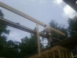 Carpenter setting a ridge beam over a new addition frame — Ice Dam Removal by Roofing Brothers in Peosta
