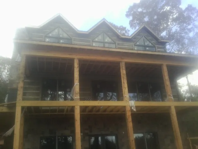 Dormers and porch framing on a large log home under construction — Roof Coating work by our crew in Peosta