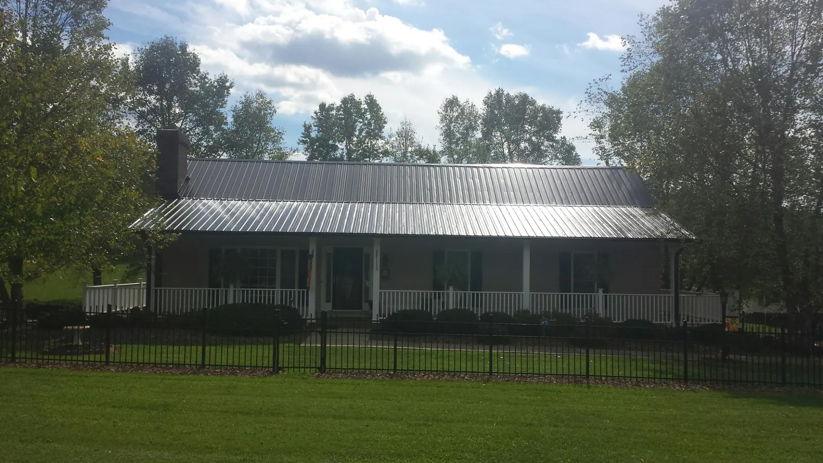 Gray metal roof on a brick ranch with a full width front porch — Gutter Guard Installation work by our crew in Peosta