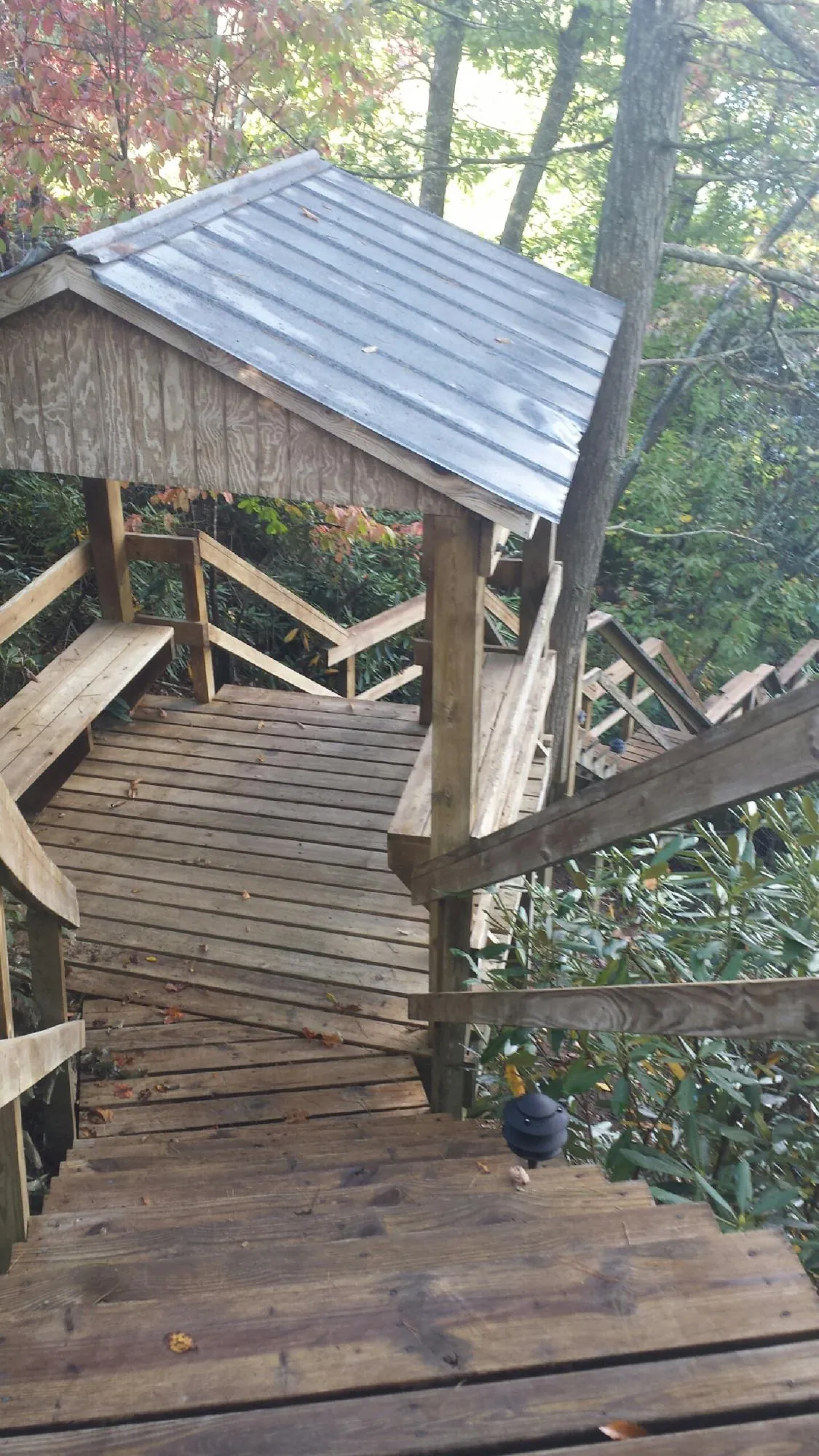 Metal roofed shelter over wooden steps on a wooded walkway — Skylight Repair & Installation work by our crew in Peosta
