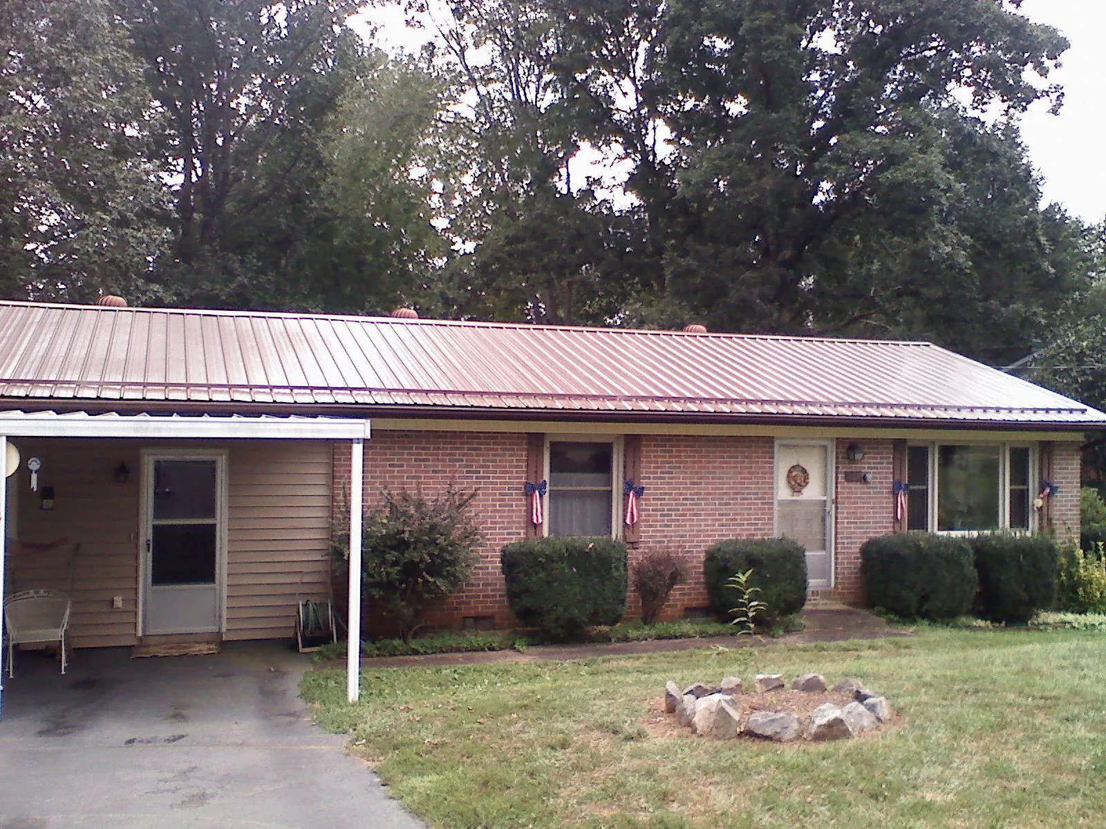 Bronze metal roof and carport on a brick ranch home — Roof Repair work by our crew in Peosta